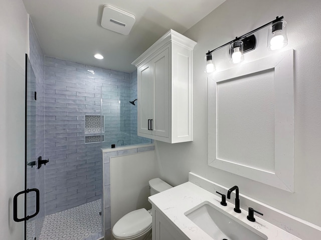 bathroom with a shower with shower door, vanity, and toilet