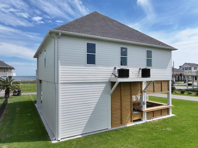 rear view of house featuring central AC and a lawn