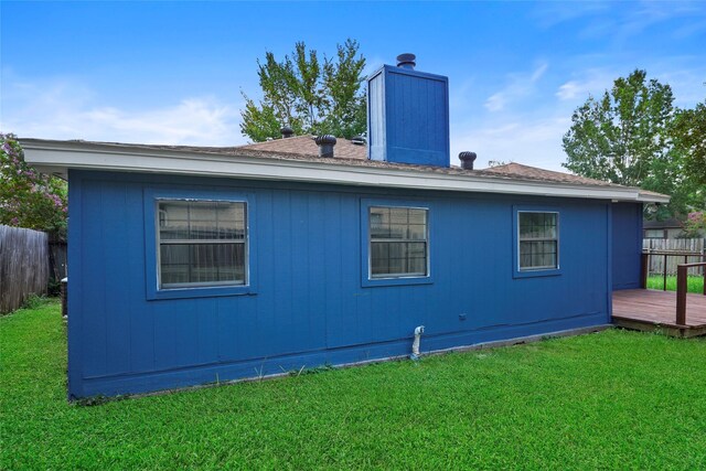 rear view of property featuring a deck and a lawn