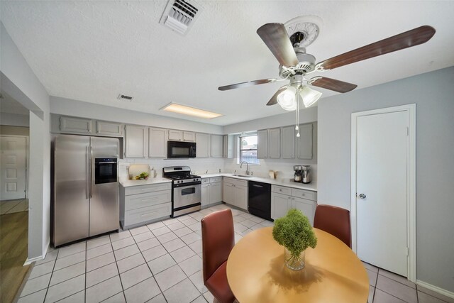 kitchen with sink, light tile patterned floors, ceiling fan, gray cabinets, and black appliances