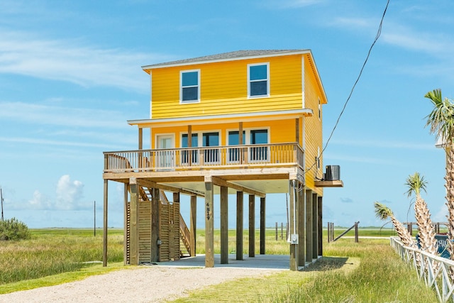 coastal inspired home with a carport, a porch, central AC unit, and a balcony