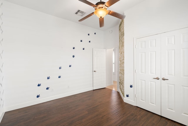 unfurnished bedroom with ceiling fan, dark wood-type flooring, a high ceiling, and a closet