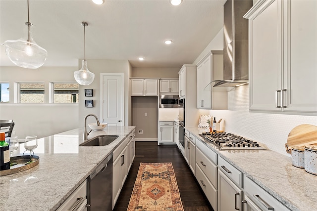 kitchen with sink, dark wood-type flooring, wall chimney range hood, light stone counters, and decorative light fixtures