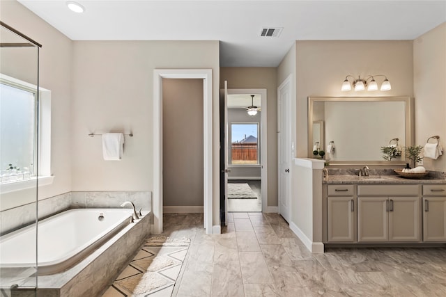 bathroom featuring tiled tub and vanity