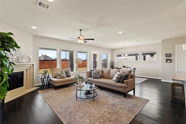 living room with a textured ceiling, dark hardwood / wood-style floors, and ceiling fan with notable chandelier