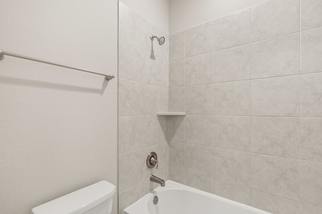 bathroom featuring toilet and tiled shower / bath