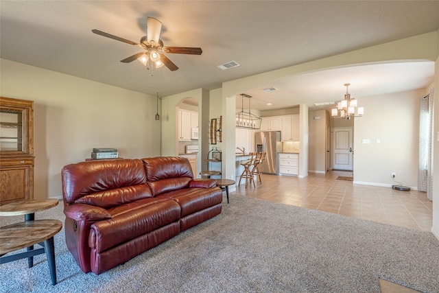 carpeted living room featuring ceiling fan with notable chandelier