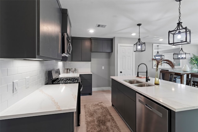 kitchen featuring pendant lighting, sink, an island with sink, and stainless steel appliances