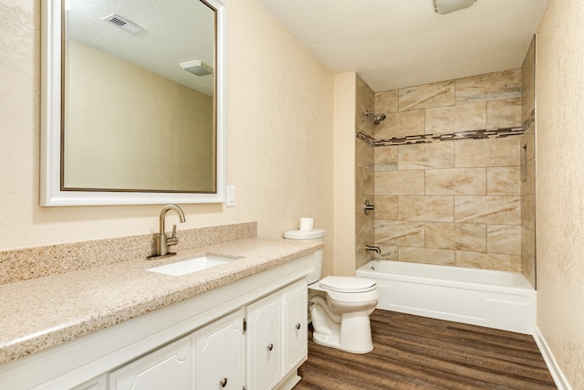 full bathroom with a textured ceiling, toilet, tiled shower / bath, hardwood / wood-style flooring, and vanity