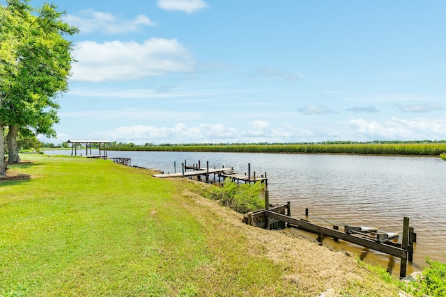 view of dock with a lawn and a water view