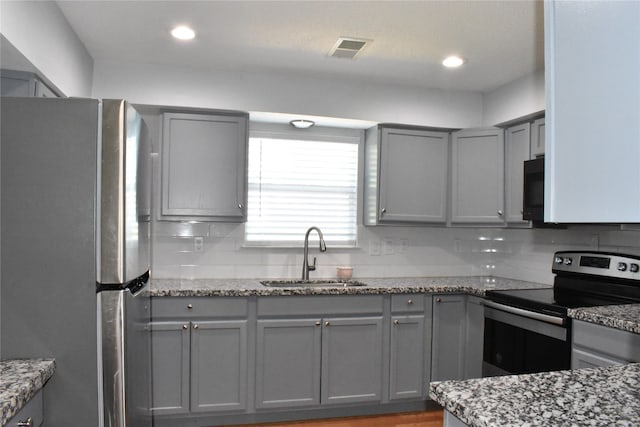 kitchen with decorative backsplash, dark stone countertops, gray cabinetry, stainless steel appliances, and sink