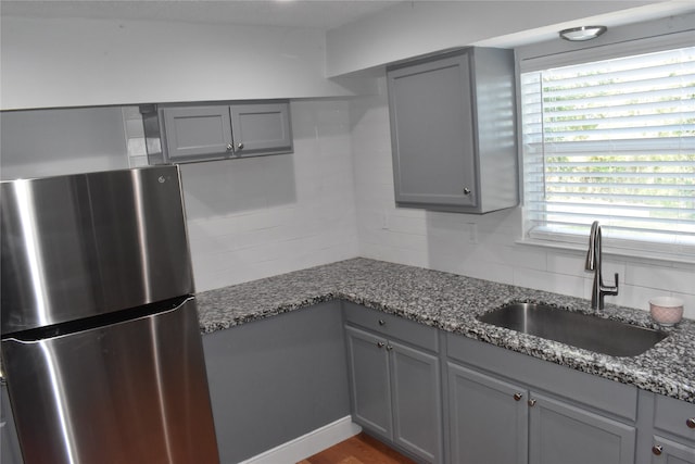 kitchen featuring stainless steel refrigerator, hardwood / wood-style flooring, gray cabinetry, tasteful backsplash, and sink