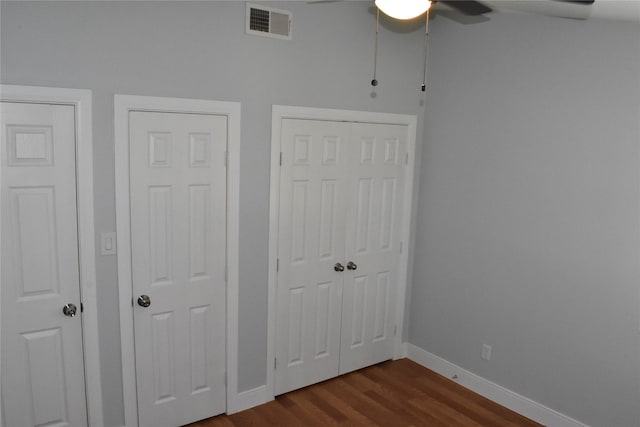 unfurnished bedroom with ceiling fan, multiple closets, and hardwood / wood-style floors