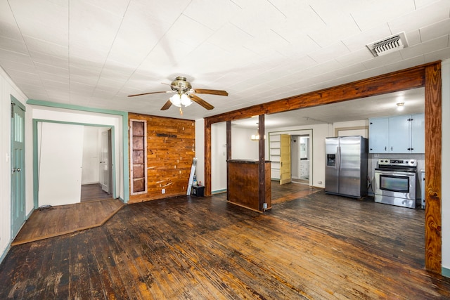 kitchen with dark hardwood / wood-style floors, wood walls, stainless steel appliances, and ceiling fan