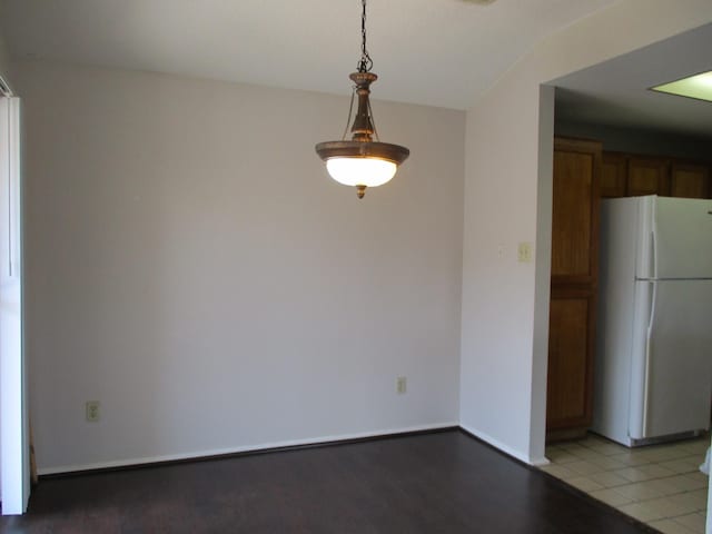 kitchen featuring tile patterned flooring, hanging light fixtures, and white refrigerator