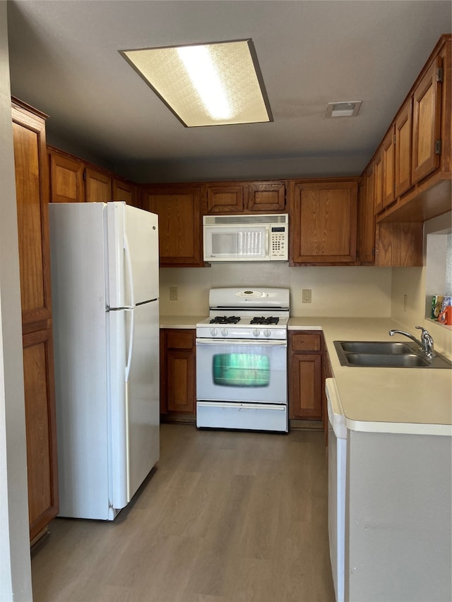 kitchen featuring sink, white appliances, and light wood-type flooring