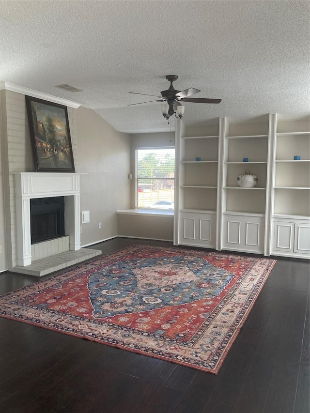 living room featuring ceiling fan, a fireplace, wood-type flooring, and a textured ceiling