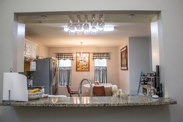 kitchen featuring sink, a chandelier, and stone countertops