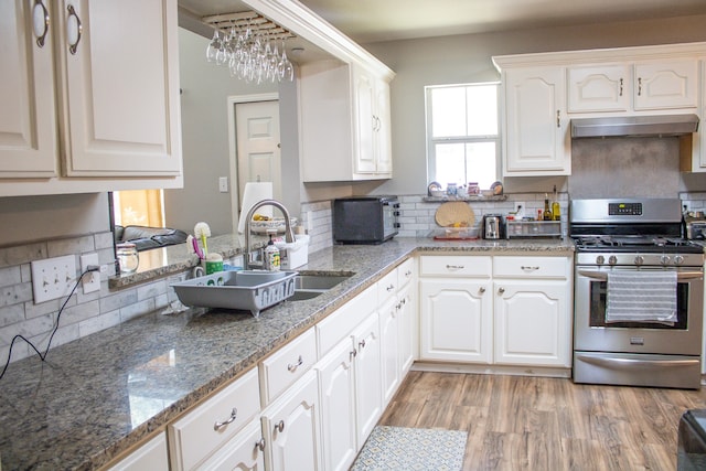 kitchen featuring white cabinets, backsplash, gas range, stone counters, and light hardwood / wood-style flooring