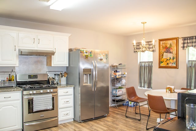 kitchen featuring a notable chandelier, appliances with stainless steel finishes, white cabinetry, dark stone counters, and light hardwood / wood-style flooring