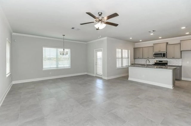 kitchen with ceiling fan with notable chandelier, decorative backsplash, an island with sink, light tile patterned flooring, and range