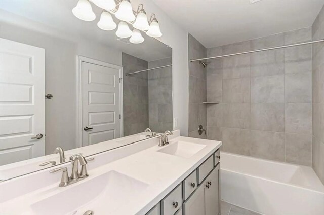 bathroom featuring dual bowl vanity and tiled shower / bath