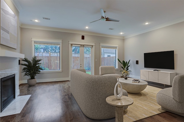 living room with ceiling fan, a fireplace, ornamental molding, and wood-type flooring