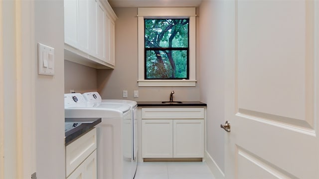 clothes washing area with light tile patterned flooring, cabinets, washing machine and clothes dryer, and sink