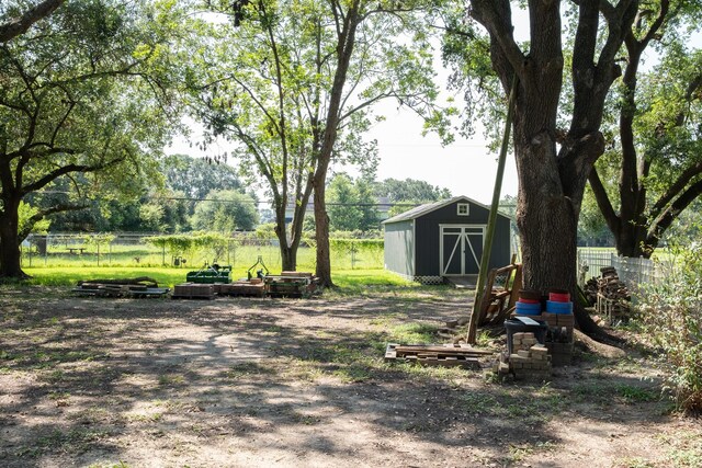 view of yard with a shed, fence, and an outbuilding