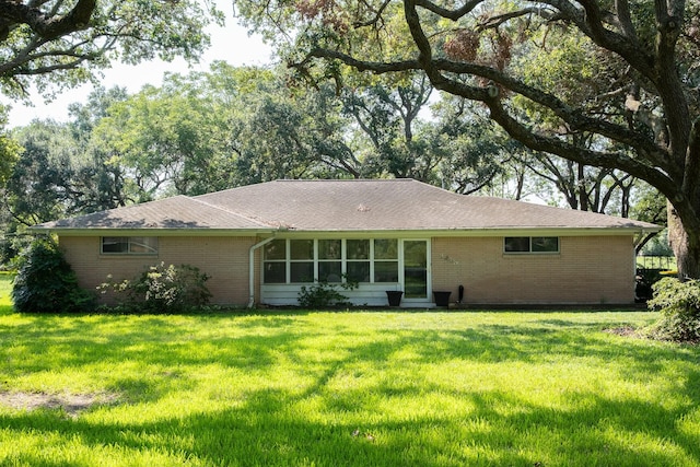 back of house with brick siding and a yard