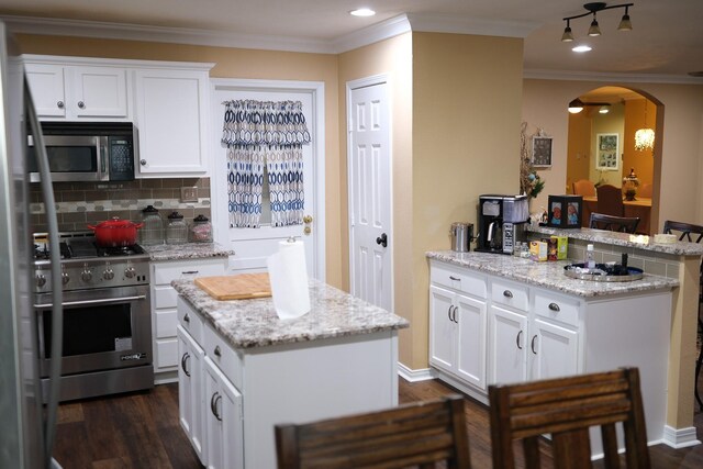 kitchen with light stone counters, white cabinetry, a kitchen island, stainless steel appliances, and track lighting