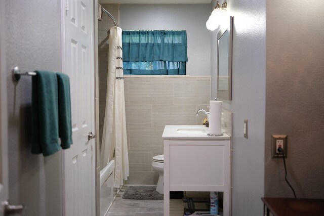 bathroom with toilet, shower / tub combo with curtain, tile walls, and vanity