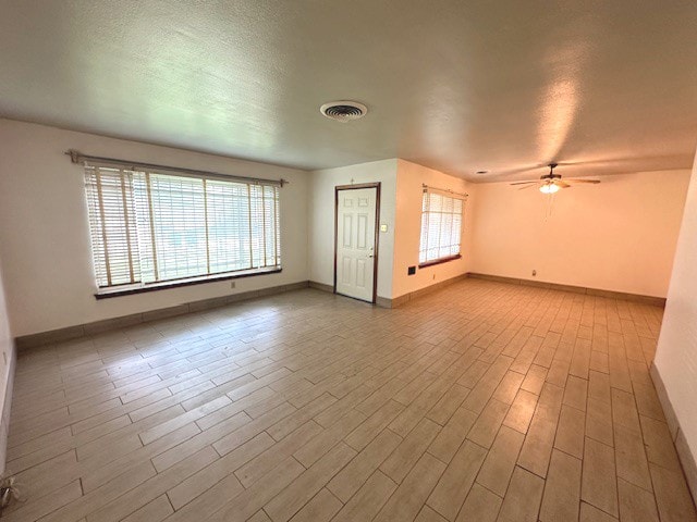 empty room with ceiling fan, hardwood / wood-style floors, and a healthy amount of sunlight