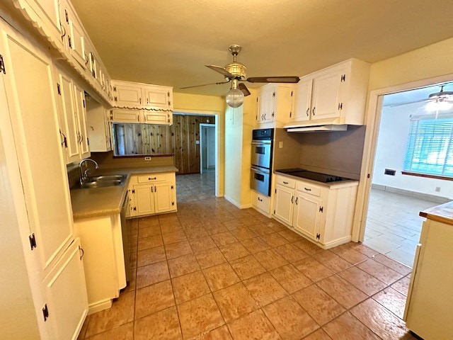 kitchen with double oven, light tile patterned flooring, white cabinets, ceiling fan, and sink