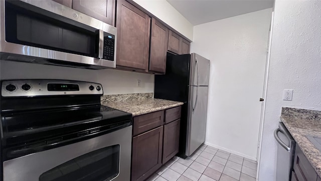 kitchen with light stone countertops, dark brown cabinets, stainless steel appliances, and light tile patterned flooring