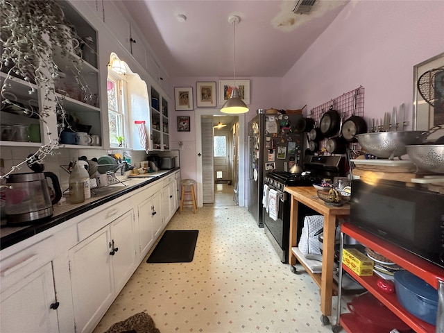 kitchen with black gas range, white cabinetry, stainless steel fridge, and decorative light fixtures