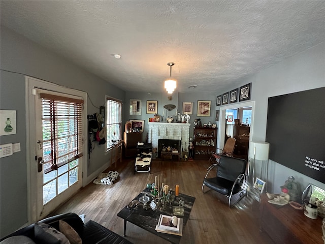 living room with a brick fireplace, dark hardwood / wood-style flooring, and a textured ceiling