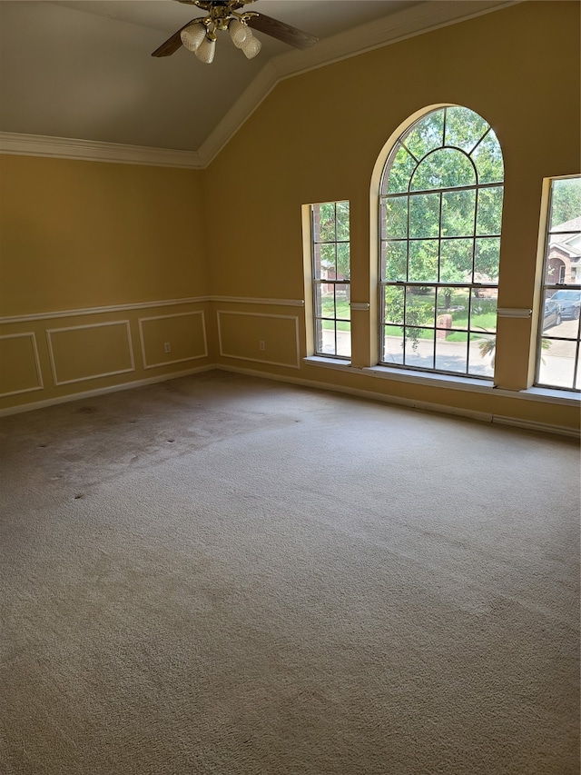 carpeted spare room featuring lofted ceiling, ornamental molding, and ceiling fan