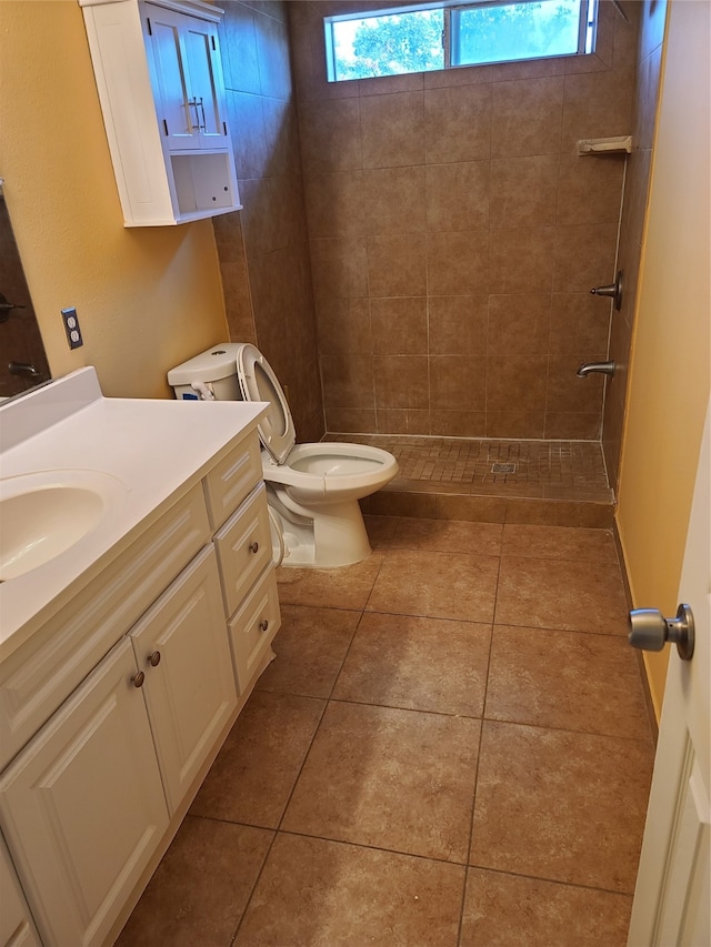 bathroom with tiled shower, toilet, vanity, and tile patterned flooring