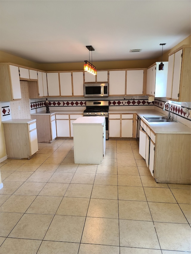 kitchen featuring appliances with stainless steel finishes, a kitchen island, sink, backsplash, and decorative light fixtures