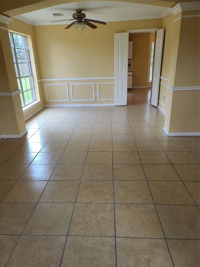 tiled spare room featuring decorative columns, crown molding, and ceiling fan