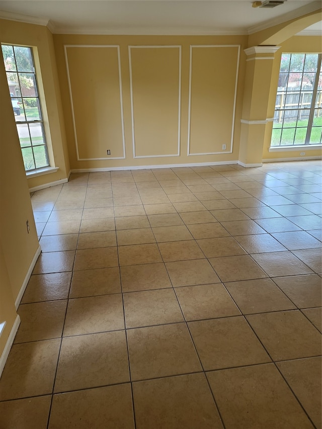 spare room with light tile patterned floors, a healthy amount of sunlight, and crown molding