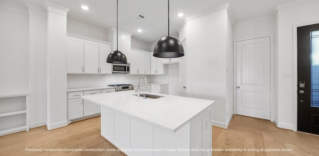 kitchen featuring a center island with sink, stainless steel appliances, light hardwood / wood-style floors, white cabinetry, and sink