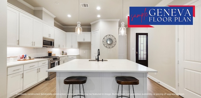 kitchen with a center island with sink, appliances with stainless steel finishes, white cabinets, light hardwood / wood-style flooring, and sink