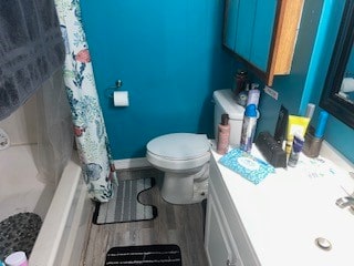 full bathroom featuring wood-type flooring, toilet, vanity, and shower / bath combination with curtain