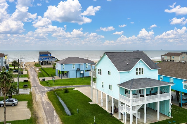 back of property featuring a balcony, a water view, a lawn, and a carport