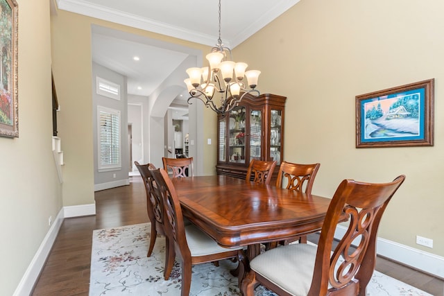 dining room with crown molding, dark wood-type flooring, and an inviting chandelier