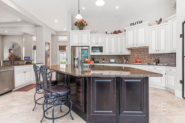 kitchen with white cabinets, a kitchen island, dark stone countertops, and appliances with stainless steel finishes