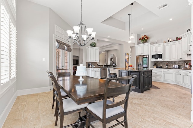 dining room featuring a towering ceiling, a tray ceiling, plenty of natural light, and a notable chandelier