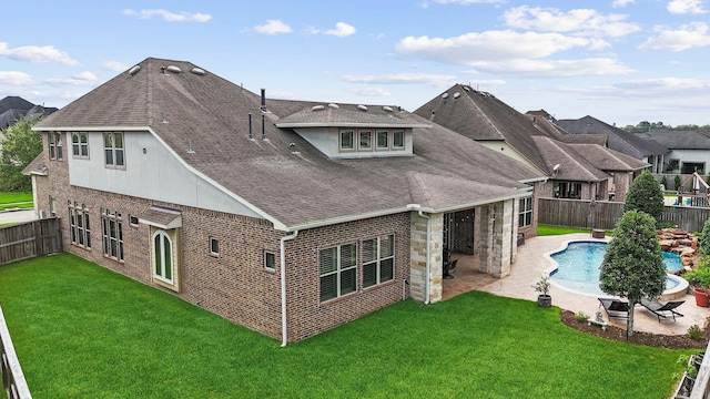 rear view of property featuring a yard, a fenced in pool, and a patio area